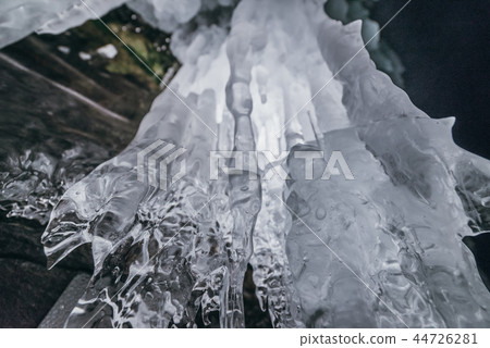 Winter Baikal. Olkhon Island. Ice grotto. Thick blue ice and icicles on the coastal rocks of Olkhon 44726281