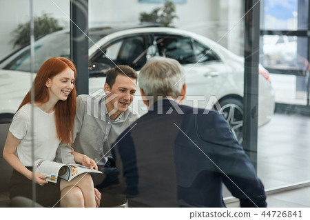 Happy beautiful couple is buying a new car at dealership. Family council 44726841