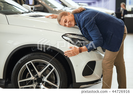 Happy man hugging new car, being completely satisfied with purchase. Happy man hugging new car, being completely satisfied with purchase. 44726916