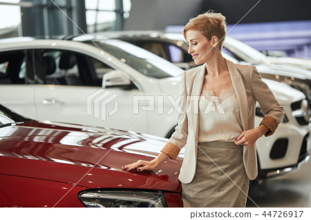 Happy caucasian woman embracing her new car at auto dealership Happy caucasian woman embracing her new car at auto dealership 44726917