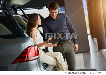 Loving smart couple choosing a car at the car dealership showroom Loving smart couple choosing a car at the car dealership showroom 44727256