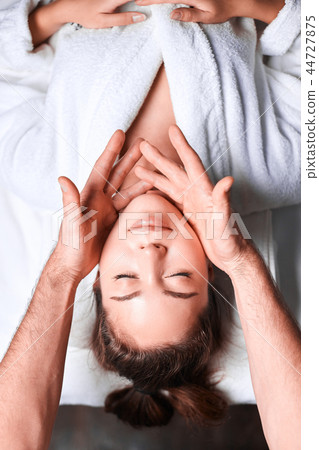 Woman enjoying anti aging facial massage. Upside down photo of relaxing woman 44727875