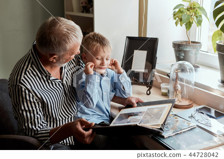 Grandfather and grandson on sofa at home. Grandpa and children watching old photos Grandfather and grandson on sofa at home. Grandpa and children watching old photos 44728042
