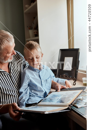 Grandfather and grandson on sofa at home. Grandpa and children watching old photos Grandfather and grandson on sofa at home. Grandpa and children watching old photos 44728509