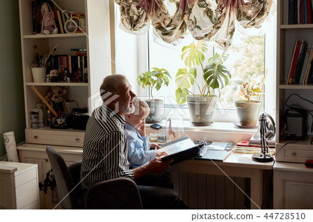 Grandfather and grandson on sofa at home. Grandpa and children watching old photos Grandfather and grandson on sofa at home. Grandpa and children watching old photos 44728510