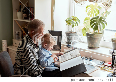 Grandfather and grandson on sofa at home. Grandpa and children watching old photos Grandfather and grandson on sofa at home. Grandpa and children watching old photos 44728511