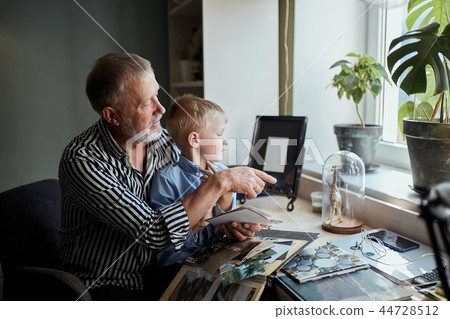 Grandfather and grandson on sofa at home. Grandpa and children watching old photos Grandfather and grandson on sofa at home. Grandpa and children watching old photos 44728512