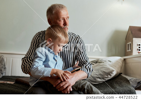 Grandfather and grandson using digital tablet while sitting on couch 44728522