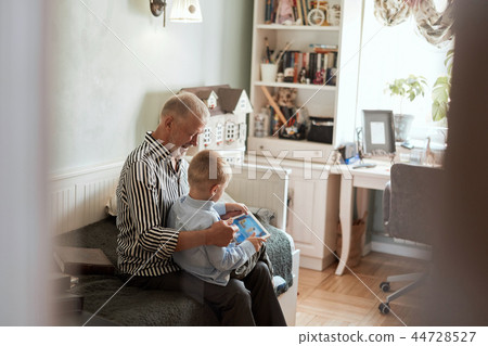Grandfather and grandson using digital tablet while sitting on couch 44728527