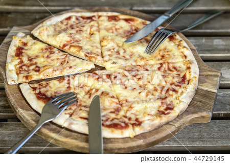 Fresh italian pizza Margherita pizza on wooden chopping board, rustic background Fresh italian pizza Margherita pizza on wooden chopping board, rustic background 44729145