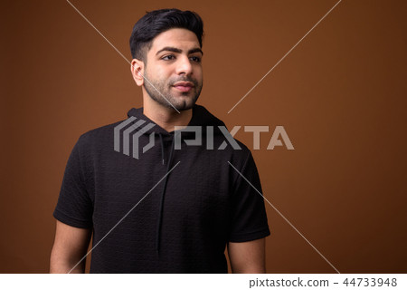 Young handsome Indian man against brown background 44733948