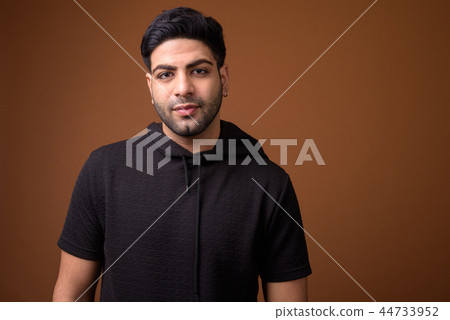 Young handsome Indian man against brown background Young handsome Indian man against brown background 44733952