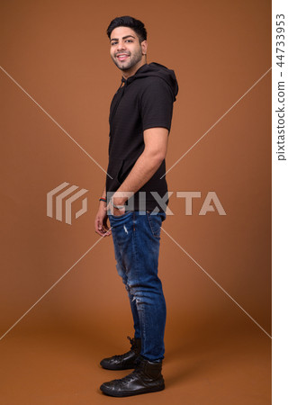 Young handsome Indian man against brown background Young handsome Indian man against brown background 44733953
