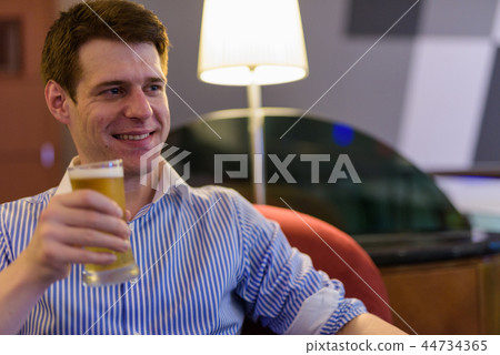 Young handsome businessman relaxing at the hotel lobby Young handsome businessman relaxing at the hotel lobby 44734365