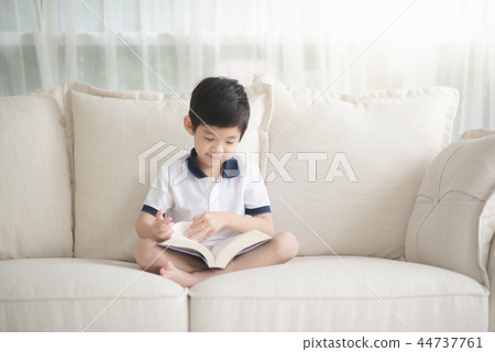 Cute Asian boy reading a book on a sofa  44737761