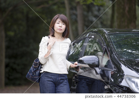 站立在汽車旁邊的中間婦女 站立在汽車旁邊的中間婦女 44738306