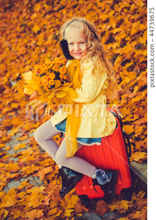 Little girl with blond hair and suitcase in autumn background Little girl with blond hair and suitcase in autumn background 44739675