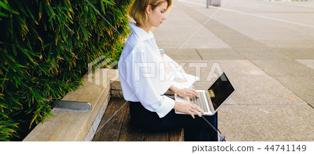 Close up face of woman typing with laptop outdoors. 44741149