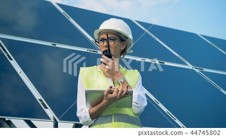 An engineer works with devices, standing on a roof near solar batteries. Alternative, green energy An engineer works with devices, standing on a roof near solar batteries. Alternative, green energy 44745802