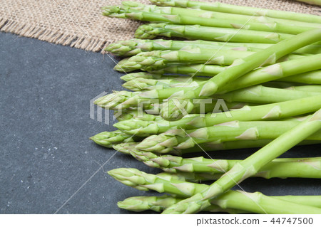 bunch of asparagus on sack over slate 44747500