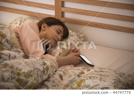 Young woman looking at smartphone in bed 44747778