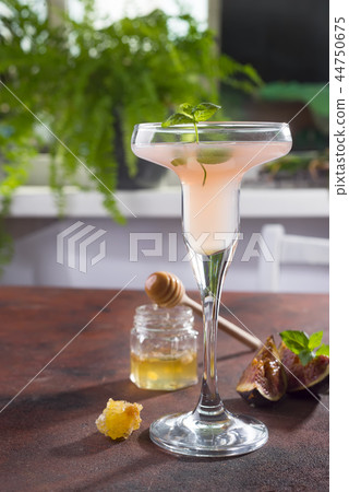 Bellini cocktail with peach and figs, honey on brown background over windows with flowers , copy 44750675