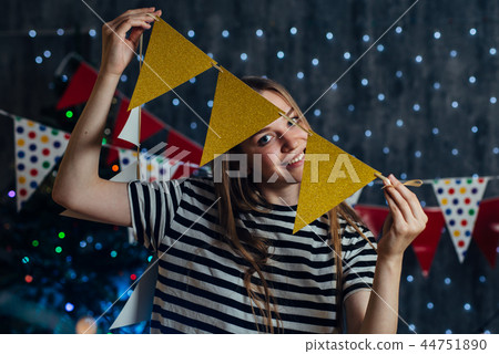 Woman at home hanging christmas lights party flags decorate items for celebration new year Woman at home hanging christmas lights party flags decorate items for celebration new year 44751890