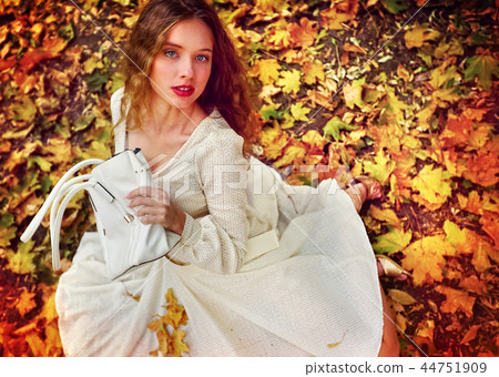 Autumn fashion dress woman sitting fall leaves city park outdoor. Autumn fashion dress woman sitting fall leaves city park outdoor. 44751909