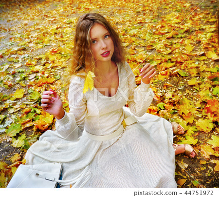 Autumn fashion dress woman sitting fall leaves city park outdoor. Autumn fashion dress woman sitting fall leaves city park outdoor. 44751972