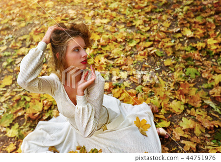 Autumn fashion dress woman sitting fall leaves city park outdoor. Autumn fashion dress woman sitting fall leaves city park outdoor. 44751976
