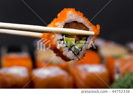 Mens hand holding wooden sticks California roll  44752336