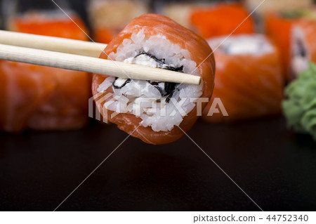 Mens hand holding wooden sticks Philadelphia roll  44752340