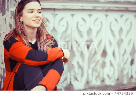 girl is sitting on a garden bench / beautiful model posing sitting in coat on bench in city park, beautiful girl 44754359