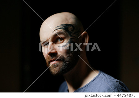 tattoo on the face, man with a tattoo, brutal bearded guy, studio portrait of a man 44754873