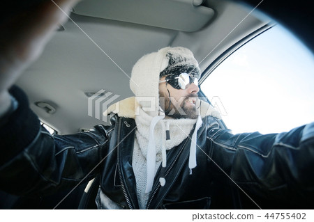 driver of the car in winter clothes, man behind the wheel, a winter journey on car, brutal man with beard on the car, professional traveler 44755402