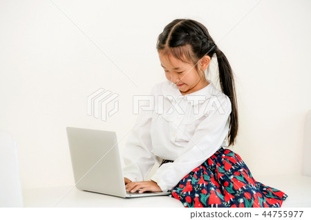 Little kid using laptop computer on white sofa. Little kid using laptop computer on white sofa. 44755977