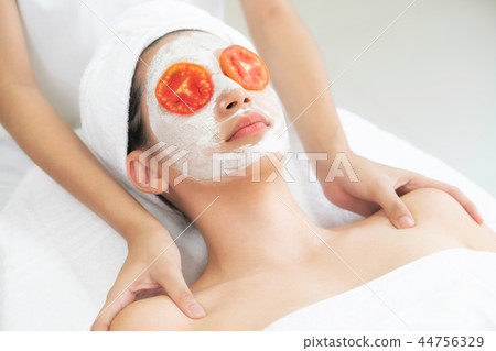 Woman get facial mask with tomato cream extract. 44756329