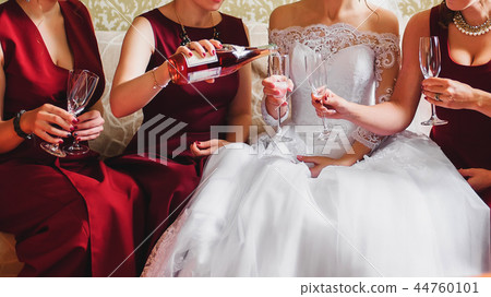 girlfriends pour champagne into glasses in their hands and celebrate wedding party 44760101