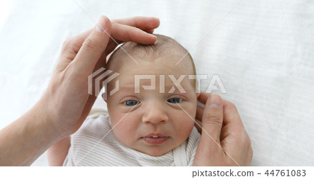 Mother stroking the child to feel the fontanel 44761083