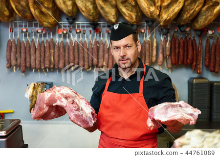 Butcher holding meat standing in a butcher shop Butcher holding meat standing in a butcher shop 44761089