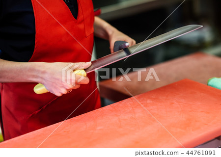 Butcher sharpening a knife in a butcher shop 44761091