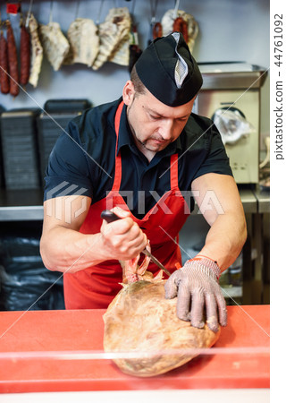 Butcher boning a ham in a modern butcher shop Butcher boning a ham in a modern butcher shop 44761092