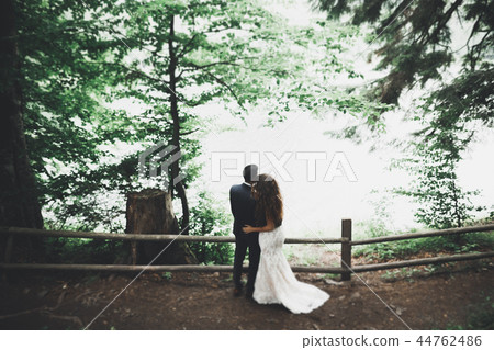 Newly married couple running and jumping in park while holding hands Newly married couple running and jumping in park while holding hands 44762486