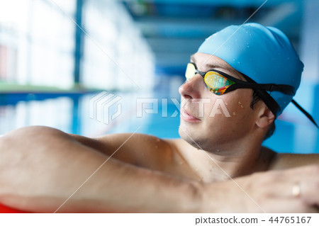 Portrait of athlete swimmer in blue cap at side in swimming pool 44765167
