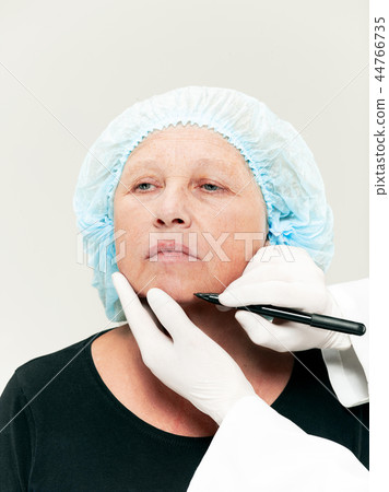 surgeon doing skin check on mid age woman before plastic surgery surgeon doing skin check on mid age woman before plastic surgery 44766735