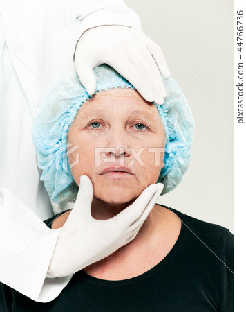 surgeon doing skin check on mid age woman before plastic surgery 44766736