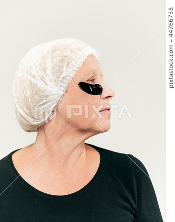 Senior woman studio looking at camera making masks under eyes Senior woman studio looking at camera making masks under eyes 44766738