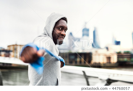 Young black sportsman exercising with elastic rubber bands in London. 44768057