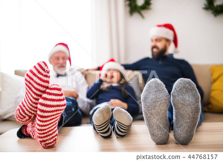 A small girl with father and grandfather sitting on a sofa at Christmas time. 44768157