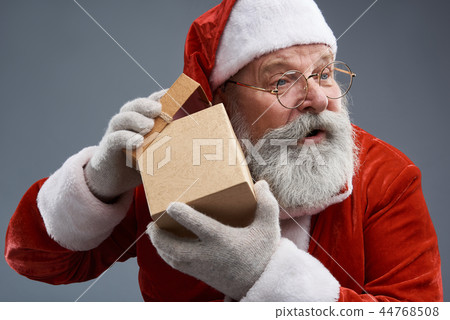 Curious Santa Claus opening gift box and listening sounds coming from it 44768508